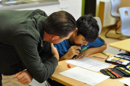 Ein Schüler arbeitet gemeinsam mit seinem Lehrer an einem Arbeitsblatt